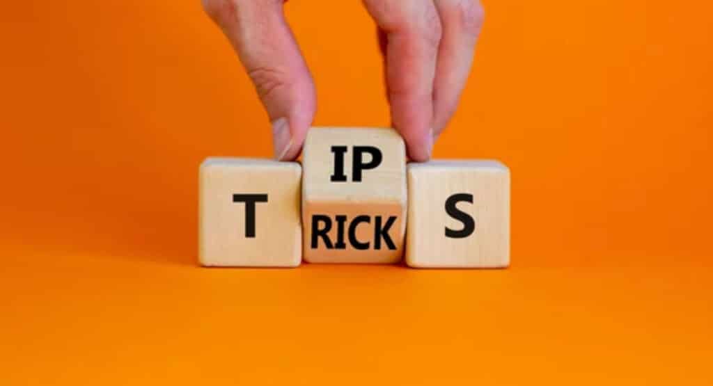 Tips and tricks symbol. Businessman turn the wooden cube and changes the word 'tips' on 'tricks'. Beautiful orange background. Business and tips and tricks concept, copy space