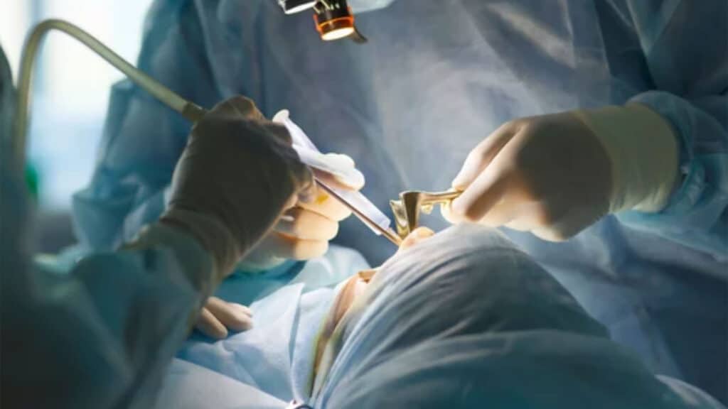 Surgeon and his assistant performing cosmetic surgery on nose in hospital operating room